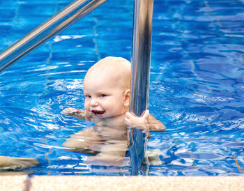 Baby boy on inflatable ring swimming in pool