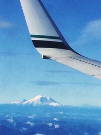 Aerial view of snowcapped mountains against blue sky