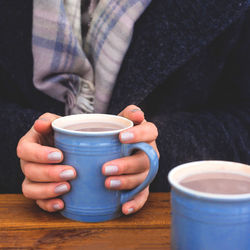 Fale hands holding cocoa cup on table