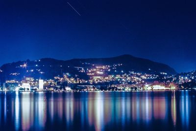 Illuminated cityscape by lake como at night