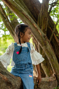 Full length of woman looking at tree trunk