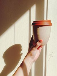 Midsection of woman holding drink against wall