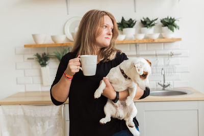 Young woman drinking dog at home