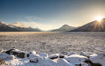 Scenic view of lake by snowcapped mountains against sky during sunset