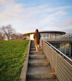 Rear view of woman walking on bridge against sky