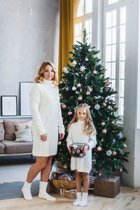 Woman standing by christmas tree at home