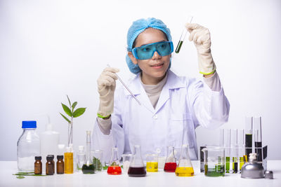 Woman experimenting chemicals against white background
