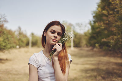 Portrait of beautiful young woman standing against plants