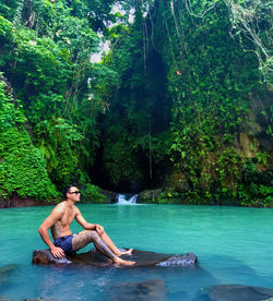 Man relaxing in swimming pool in forest