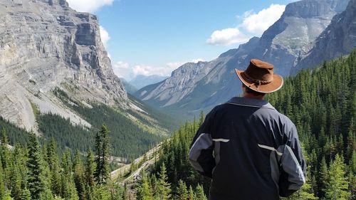 Rear view of man standing on mountain against sky