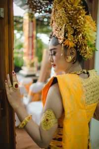 Beautiful woman wearing jewelries and traditional clothing standing at entrance