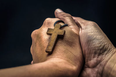 Close-up of man holding hand against black background