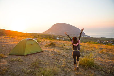 Woman meets the dawn in the mountains, rejoices in the sun. panoramic view of the mountain 