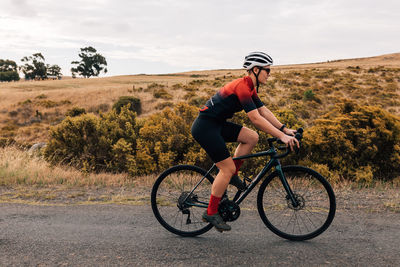 Full length of woman riding bicycle on road