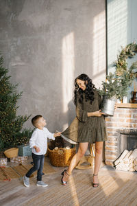 Stylish mom and little baby son are having fun during the festive time, playing near the christmas