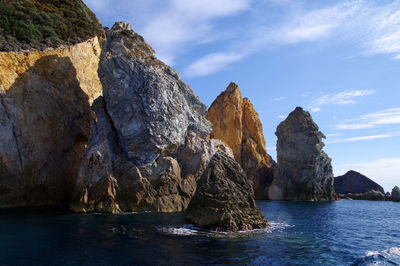 Rock formation in sea against sky