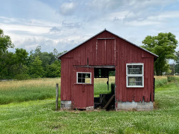 A small red barn in a field of grass.