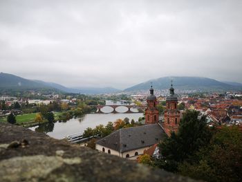 Buildings by river against sky in city