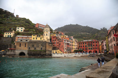 Buildings by river against sky in city