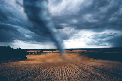 Tornado on land against storm clouds