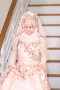 Beautiful woman wearing hijab and wedding dress on steps