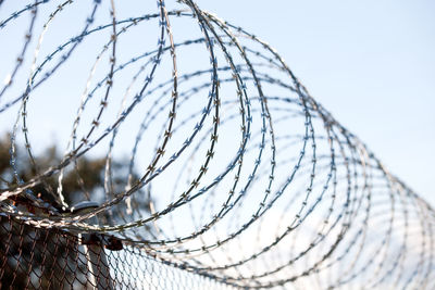 Close-up of barbed wire fence against sky