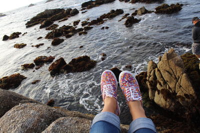 Low section of woman sitting on rocky shore