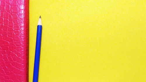 High angle view of colored pencils against yellow background