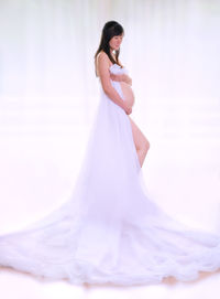 Side view of woman standing against white background