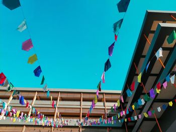 Low angle view of flags hanging against clear blue sky
