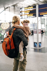 Family waiting near airport sign, arrival and departure area. man and happy girl ready to go by