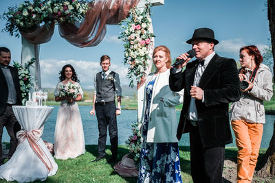 People in traditional clothing standing by flowers