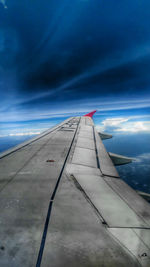 Airplane wing against cloudy sky