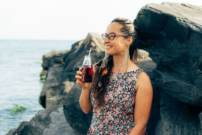 Woman looking away while drinking juice outdoors