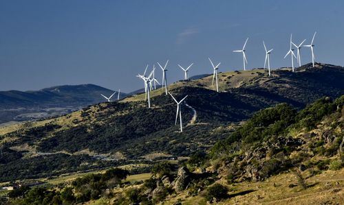 Wind turbines on land against sky