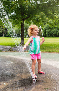 Little happy children playing with water at splash pad playground in public park in summer