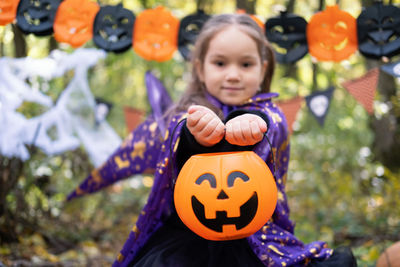 Halloween. cute little girl in witch costume with jack o lantern having fun outdoor