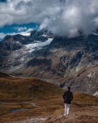 Rear view of man standing on mountain against sky