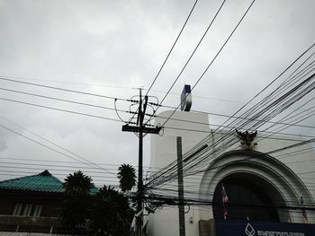 Low angle view of electricity pylon against buildings
