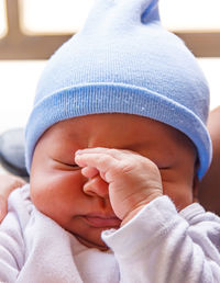 Newborn baby touching his face with his hands