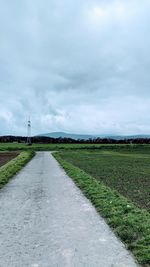 Road amidst field against sky