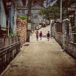 Children running on street amidst houses