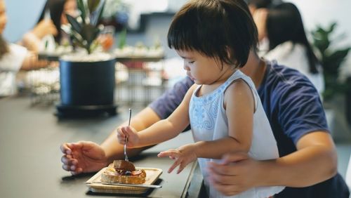 Cute girl with father eating food at restaurant