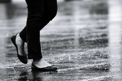 Low section of man standing on wet lake