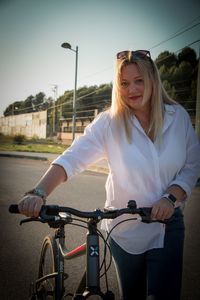 Portrait of a young blond woman carrying the bicycle