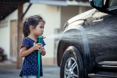 Girl spraying water on car