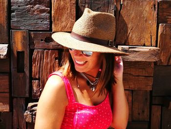 Portrait of smiling young woman wearing hat sitting outdoors