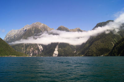 Scenic view of sea and mountains against clear blue sky