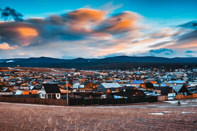 Scenic view of beach by buildings against sky during sunset