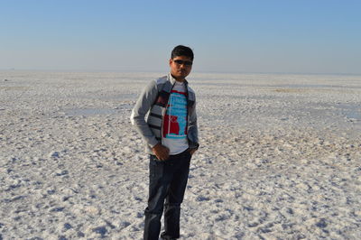 Portrait of young man standing on salt flat against sky